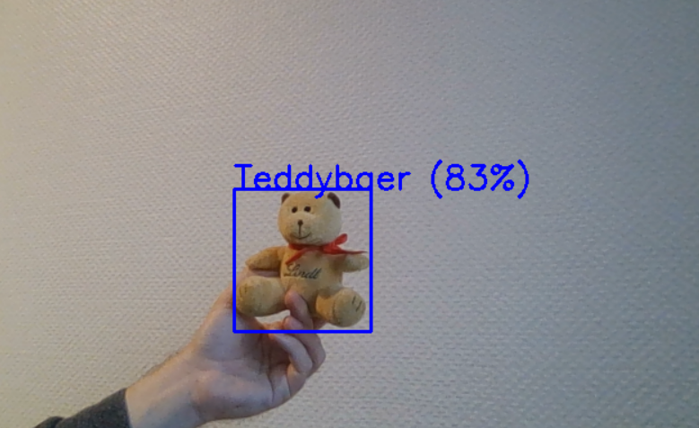 teddy_yolo Das Bild zeigt einen kleinen Teddy Bär, der von dem Yolo-Modell zu 83 Prozent als solcher erkannt wurde.